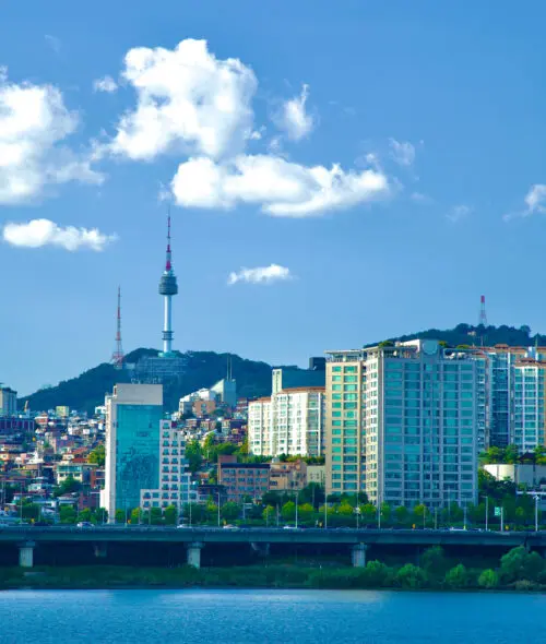 Seoul, South Korea - October 1, 2023: A picturesque scene of Itaewon neighborhood perched on a low hill along the banks of the Han River, framed by a blue sky dotted with a few clouds.