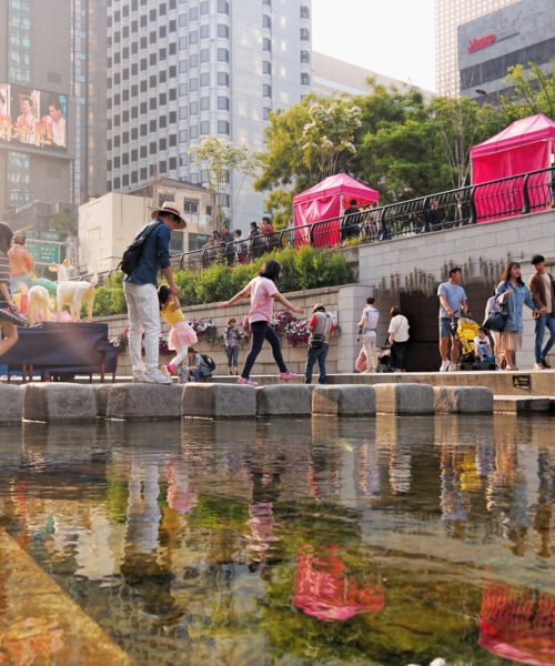 Seoul, South Korea - May 2019:  Scenic reflection view of people on the Cheonggye Stream (Cheonggyecheon) at sunset