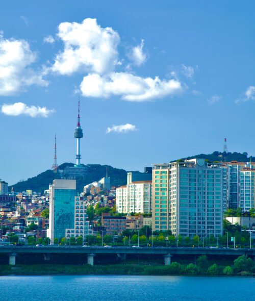 Seoul, South Korea - October 1, 2023: A picturesque scene of Itaewon neighborhood perched on a low hill along the banks of the Han River, framed by a blue sky dotted with a few clouds.